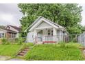 Quaint single-story home with a fenced yard and inviting front steps to a covered porch at 1938 N Dearborn St, Indianapolis, IN 46218