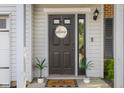 Close-up of front door with 'Welcome' sign, potted plants, and modern exterior lighting at 2247 Rolling Hill Ct, Columbus, IN 47201