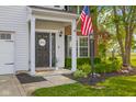 Inviting front porch with a welcoming American flag, landscaped garden, and covered entryway at 2247 Rolling Hill Ct, Columbus, IN 47201