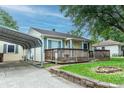 Cozy home with a covered carport, yellow siding, green shutters, front porch, and well-kept landscaping at 2620 13Th St, Columbus, IN 47201