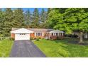 Red brick home with an attached garage, surrounded by a lush green lawn and mature trees, providing a serene setting at 703 Chapel Hill W Dr, Indianapolis, IN 46214