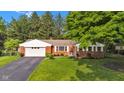 Beautiful red brick home with an attached garage, complemented by a lush green lawn and mature trees at 703 Chapel Hill W Dr, Indianapolis, IN 46214