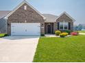 A brick house featuring a two-car garage, a green lawn and colorful landscaping at 9001 Fitzgerald Dr, Indianapolis, IN 46239