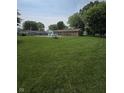 Large grassy backyard with a pool, fenced in with mature trees at 9984 W Sunset Ln, Elwood, IN 46036