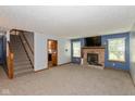 Cozy living room featuring a brick fireplace, plush carpet, and stairs at 1159 Oak Leaf Rd, Franklin, IN 46131