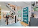 Bright entryway with an updated teal door, modern staircase, and stylish geometric tile flooring at 1810 S Raceway Rd, Indianapolis, IN 46231