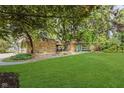 Expansive front yard with mature trees and stone facade house, features a lush lawn and inviting atmosphere at 1810 S Raceway Rd, Indianapolis, IN 46231