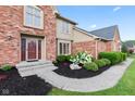 Welcoming front entrance with a brick facade, mature shrubs, and a concrete walkway at 1826 Spruce Dr, Carmel, IN 46033