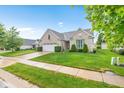 Attractive brick home featuring a manicured lawn, mature landscaping, and an attached two-car garage at 18991 Round Lake Rd, Noblesville, IN 46060