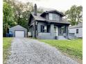 View of the gray home with a detached garage and gravel driveway at 2720 S Taft Ave, Indianapolis, IN 46241
