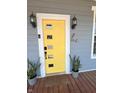 Modern yellow front door with decorative windows, flanked by potted plants and stylish sconces at 302 Penn St, Westfield, IN 46074