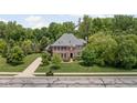 Beautiful aerial view of brick home with professionally landscaped lawn and mature trees at 4529 Panthera Leo Dr, Carmel, IN 46074