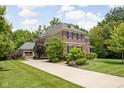 View of the house with attached garage and long driveway surrounded by trees and manicured lawn at 4529 Panthera Leo Dr, Carmel, IN 46074