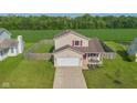 Aerial view of the charming home, showcasing its spacious yard, two-car garage, and proximity to the treeline at 4605 Clairmont Dr, Columbus, IN 47203