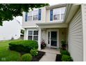 Inviting front entrance with a white-trimmed door, manicured bushes, and vibrant potted flowers at 5456 Reston Dr, Plainfield, IN 46168