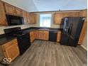 Well-lit kitchen featuring oak cabinets, black appliances, and durable laminate countertops at 5825 Sapelo Dr, Indianapolis, IN 46237