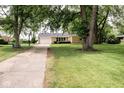 Lovely ranch style home with a long driveway leading to an attached garage and front yard at 6180 Winnpeny Ln, Indianapolis, IN 46220