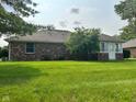 Spacious backyard featuring a well-maintained lawn, mature trees, and a brick home with a screened patio at 641 S Grant St, Brownsburg, IN 46112