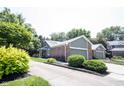 Charming home featuring brick accents, attached garage, manicured lawn, and vibrant flowering shrubbery at 8023 Talliho Dr, Indianapolis, IN 46256