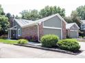 Charming home featuring brick accents, attached garage, manicured lawn, and vibrant flowering shrubbery at 8023 Talliho Dr, Indianapolis, IN 46256