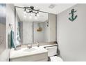 A compact bathroom featuring a sink, toilet, mirror, and a coastal themed decor at 8121 Bromley Pl, Indianapolis, IN 46219