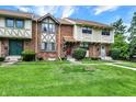 Brick townhomes with green lawns, sidewalks, and various architectural details under a blue sky at 8121 Bromley Pl, Indianapolis, IN 46219