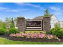 A welcoming 'Trails at Grassy Creek' sign surrounded by vibrant pink flowers and lush greenery at 10118 Falls Canyon Ln, Indianapolis, IN 46229
