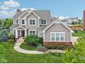 Beautiful two-story home with manicured lawn, colorful landscaping, and a paved walkway at 10806 Solis Cir, Fishers, IN 46038