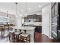 Stylish kitchen island with granite countertops, stainless steel sink, modern lighting, and seating for three at 10806 Solis Cir, Fishers, IN 46038