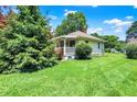 Well-kept home showcasing a verdant lawn, mature trees, and a charming porch at 1411 N Kenmore Rd, Indianapolis, IN 46219
