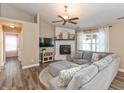 Cozy living room with a fireplace, ceiling fan, wood-look floors, and a comfortable gray sectional sofa at 1450 Millridge Dr, Greenwood, IN 46143