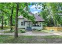 View of a charming home with a small porch and surrounding greenery, framed by mature trees at 1511 E Edwards Ave, Indianapolis, IN 46227