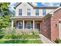 Close-up of the front entrance with brickwork, a dark-colored front door, and neatly arranged flower beds at 2211 Willowview Dr, Indianapolis, IN 46239