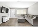 Bright living room with a large gray sofa, entertainment console, and laminate flooring at 258 N Green Springs Rd, Indianapolis, IN 46214