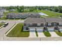 Aerial view showcasing townhomes with attached garages and lush green spaces with a pond in the background at 2892 Maricopa Blvd, Whitestown, IN 46075