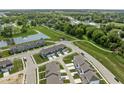 Wide aerial view of a neighborhood featuring townhomes, green spaces, a pond, and mature trees at 2892 Maricopa Blvd, Whitestown, IN 46075