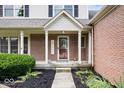 Charming front porch with brick accents, decorative door, and manicured landscaping with black mulch at 3823 Vanguard Cir, Carmel, IN 46032