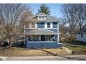 Charming two-story home features a covered front porch, gray roof, and a blue exterior at 6101 Broadway St, Indianapolis, IN 46220