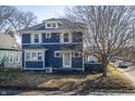 Charming blue two-story home with white framed windows and dormant landscaping at 6101 Broadway St, Indianapolis, IN 46220
