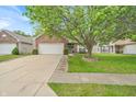 This home features a brick and vinyl exterior, a well-manicured lawn, and a two-car garage at 8315 Exton Rd, Indianapolis, IN 46239
