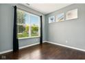 Bedroom with a large window and dark wood floors. Black curtains frame the window at 10606 Glenwyck Pl, Noblesville, IN 46060