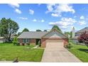 Well-manicured lawn complements this inviting brick home with an attached garage and vibrant green accents at 11026 Clearspring Way, Indianapolis, IN 46239