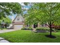 Charming brick two-story home with manicured lawn and mature trees in front yard at 1345 Lewiston Dr, Westfield, IN 46074