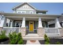 Inviting front porch with stone pillars, white railing, and a vibrant yellow front door at 14982 Dawnhaven Dr, Westfield, IN 46074