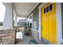Close-up of the cozy front porch featuring stylish seating, pineapple decor and a bright yellow door at 14982 Dawnhaven Dr, Westfield, IN 46074