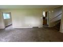 Spacious living room showing staircase and entrances to multiple rooms and neutral carpet at 1749 N Graham Ave, Indianapolis, IN 46218