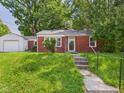 A cozy brick house with a well-manicured front yard and a detached garage at 220 Central Ave, Anderson, IN 46012