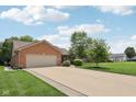 Attractive brick home with a spacious driveway, two-car garage, and lush green lawn at 3571 S Cedar Creek Ln, New Palestine, IN 46163