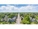 An aerial view of a residential street showcasing tree coverage and houses, with a city skyline in the distance at 4715 E New York St, Indianapolis, IN 46201