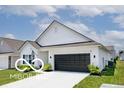 Side view of a modern single-story home with black garage door and a well-maintained lawn at 4726 Amber Wood Ln, Indianapolis, IN 46235
